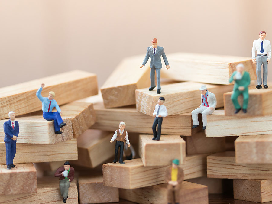 business expansion depiction in customer support miniature figures customers sitting on wooden pegs