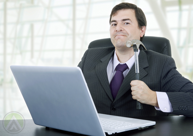 businessman holding hammer about to hit laptop