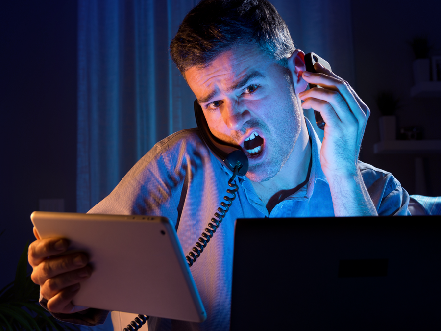 busy man at home using tablet laptop on the phone with customer service agent