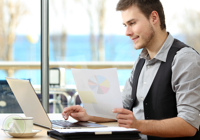 employee working on laptop with printed document