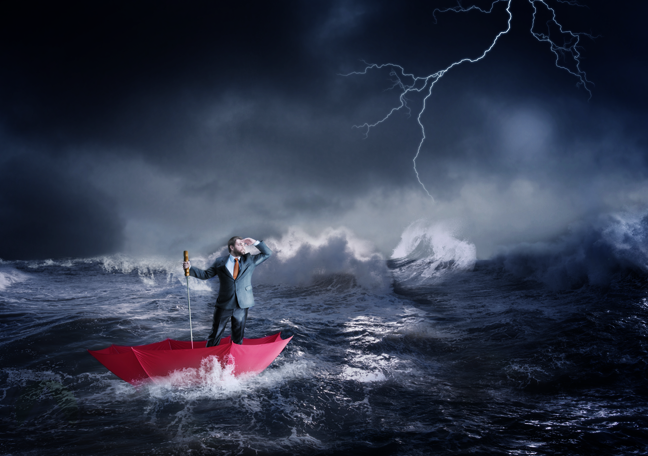 business executive sailing in stormy waters on red umbrella