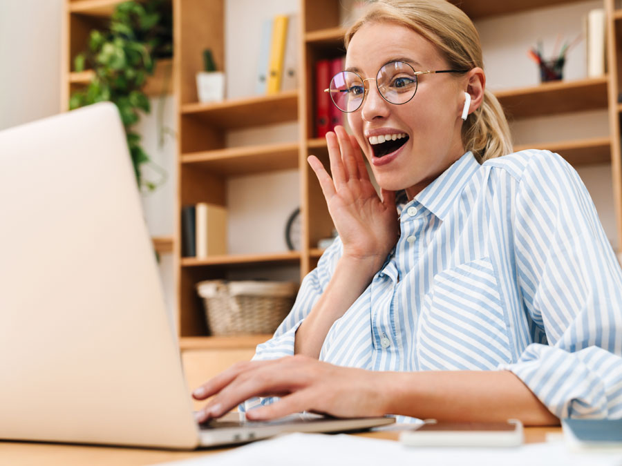 delighted woman in glasses using laptop