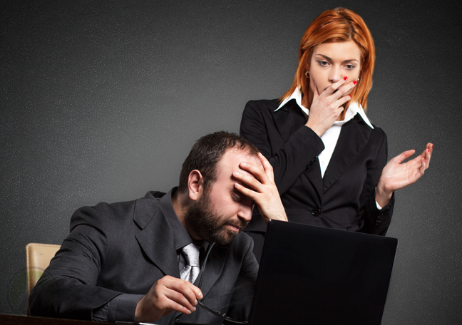 facepalming businessman by laptop shocked coworker hand to mouth