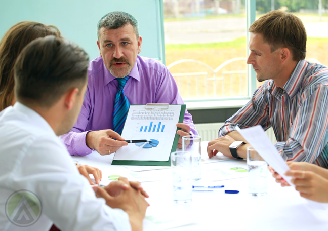 middle aged boss presenting chart to younger team