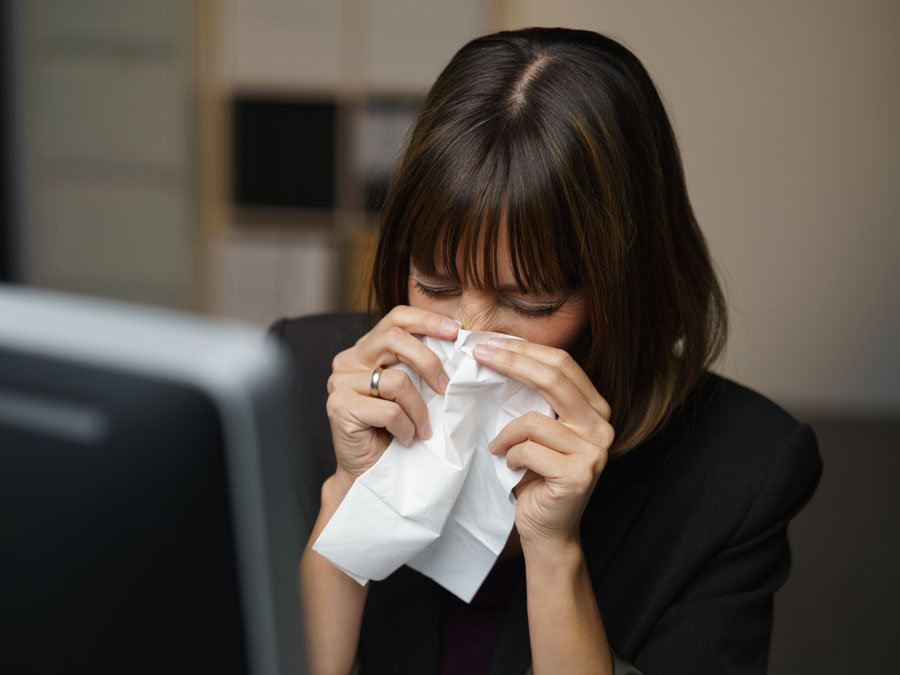 sick call center agent at work sneezing blowing nose