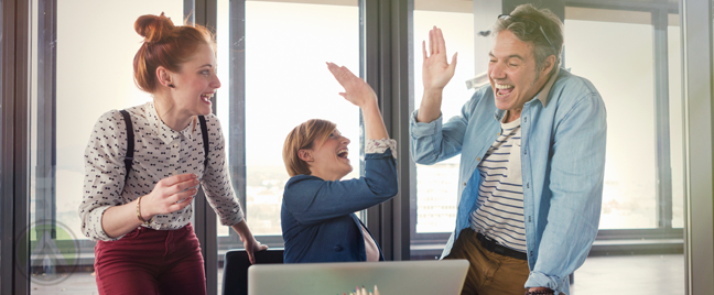 young business team high fiving by laptop