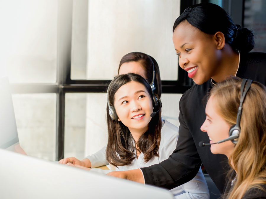 BPO team leader helping call center agents by office computer