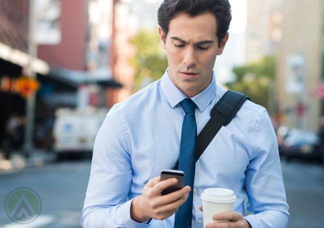 businessman walking street holding cup looking smartphone