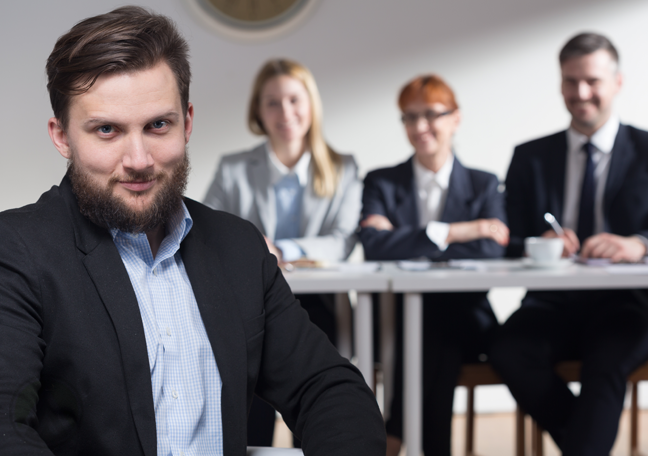 confident job applicant sitting with job interview panel in back