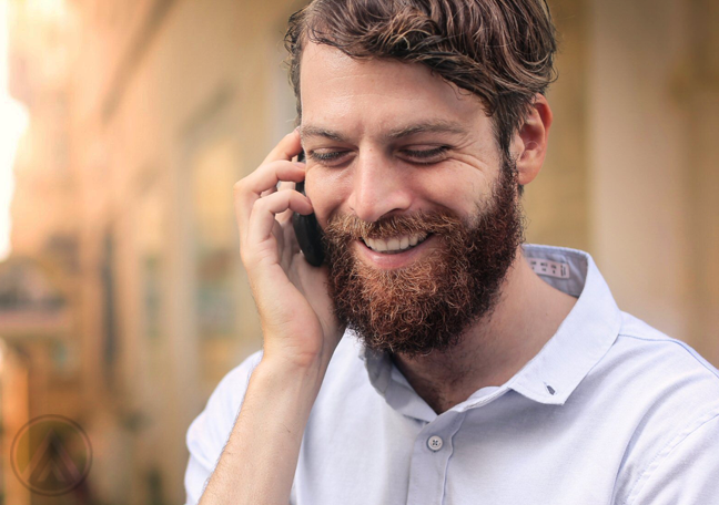 smiling bearded man in phone call