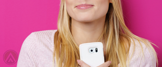 smiling blond woman hugging smartphone