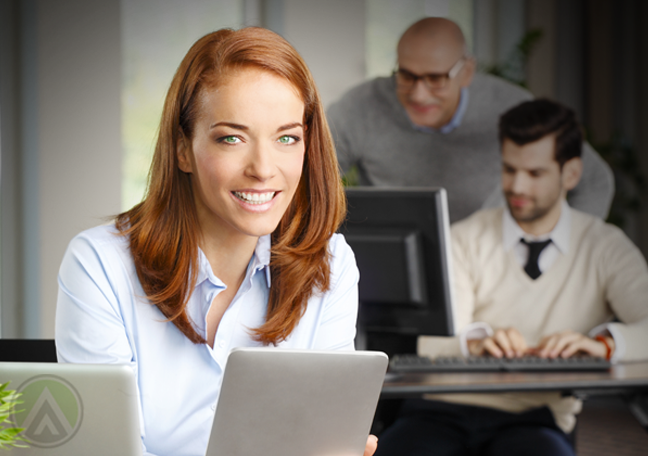 smiling female employee using tablet with coworkers in background