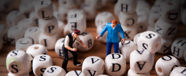 miniature business figures standing in middle of boggle blocks