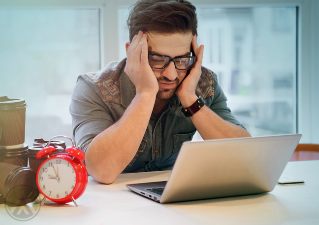 office worker with headache using laptop with red alarm clock coffee cups