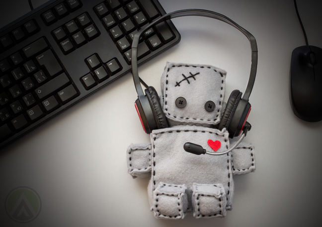 rag doll with headphones on computer table with keyboard mouse