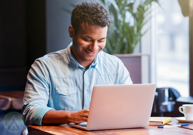 smiling businessman working on laptop in office by window