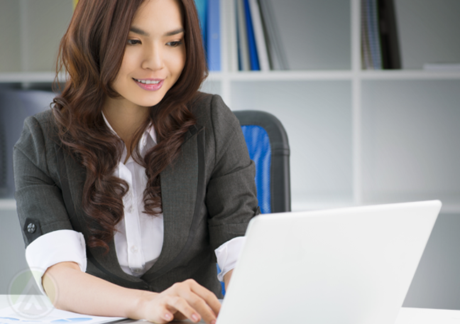 smiling young employee using laptop in office