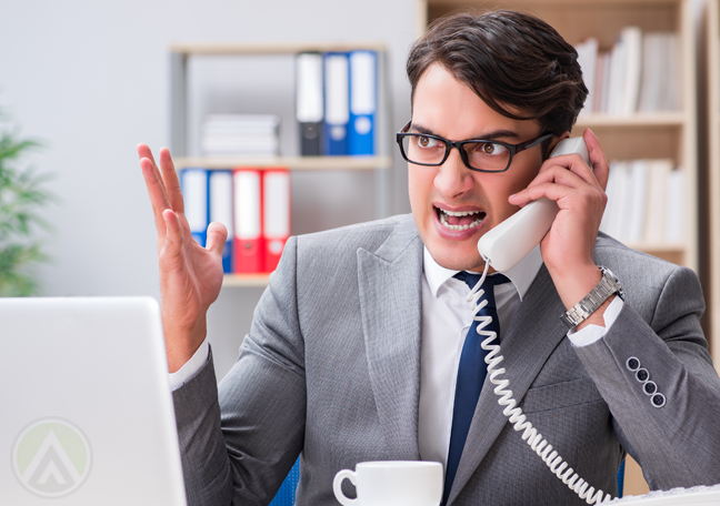 businessman complaining on phone in front of laptop and tea cup