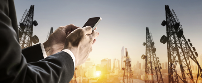 businessman using smartphone outdoors view of communciations cell towers