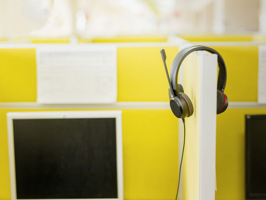 call center headphones haniging on yellow table divider