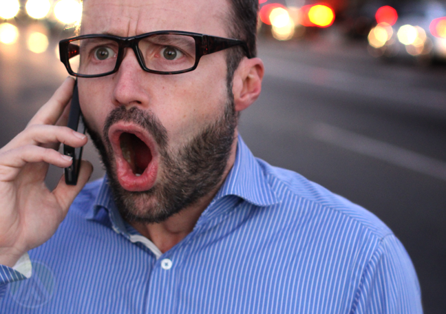 frustrated man in glasses shouting into smartphone