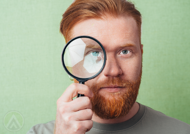 young man looking through magnifying lens