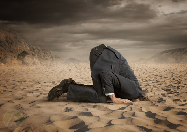 businessman hiding head in desert