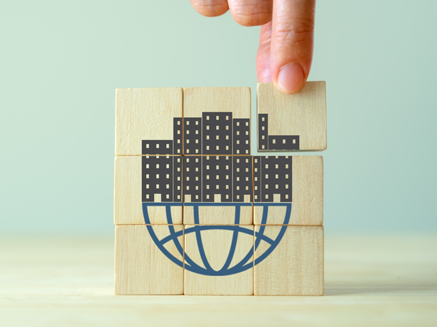 Startup Company going global depiction hand building wood blocks with globe office buildings