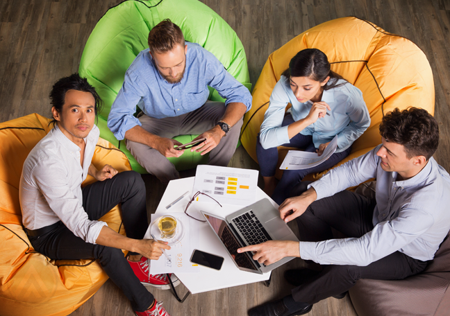 office employee working together sitting on colorful bean bag chairs showing teamwork