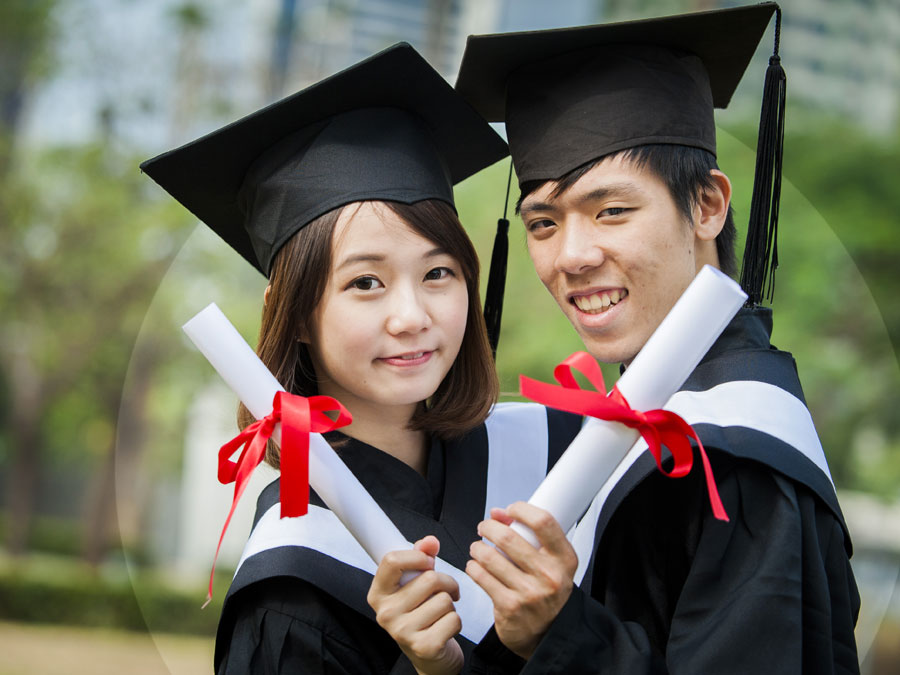 chinese asian couple graduates wearing graduation gown cap