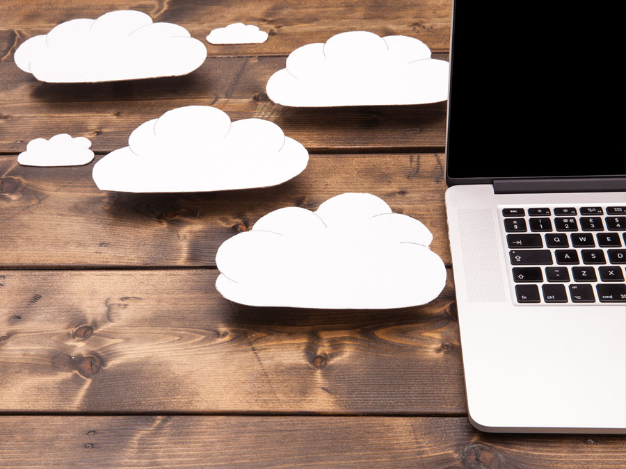 macbook laptop on table with paper cutout clouds concept cloud computing