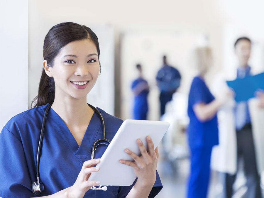 smiling Chinese healthcare provider nurse holding computer tablet in hospital