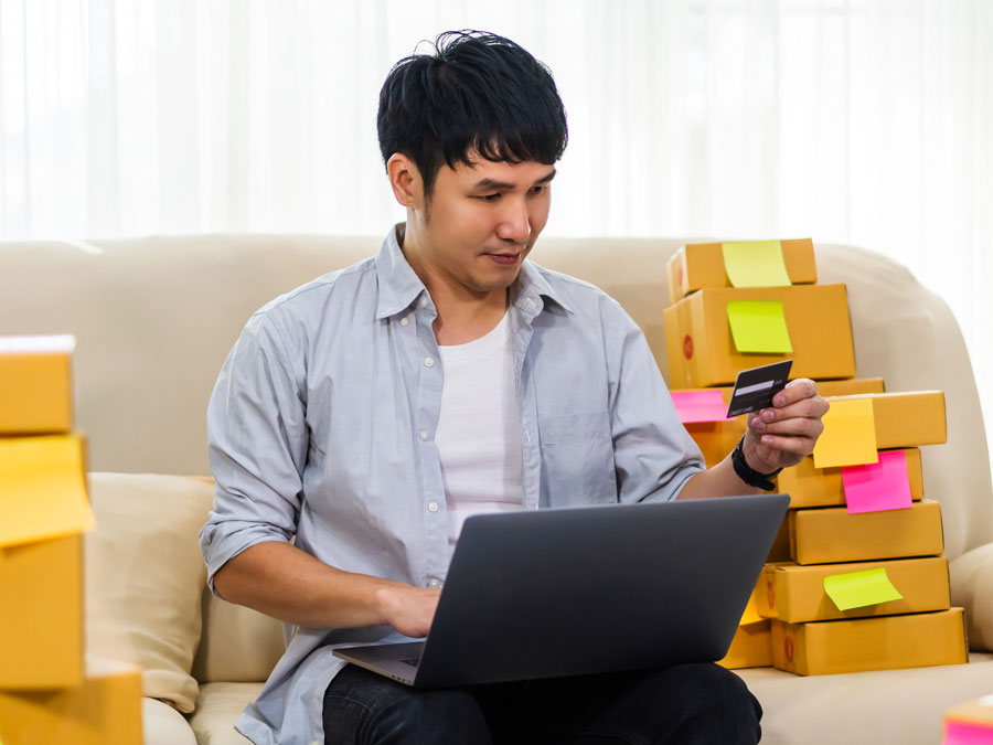 young chinese asian holding credit card doing online shopping ecommerce boxes