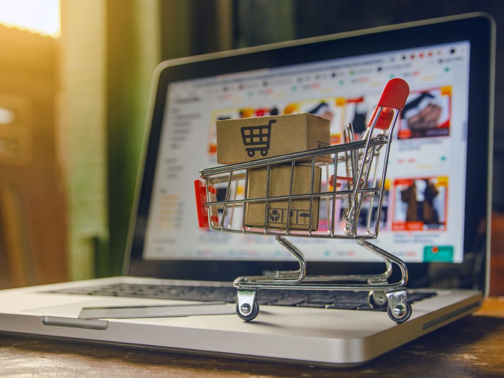 tiny shopping cart with packages on laptop on e-commerce website