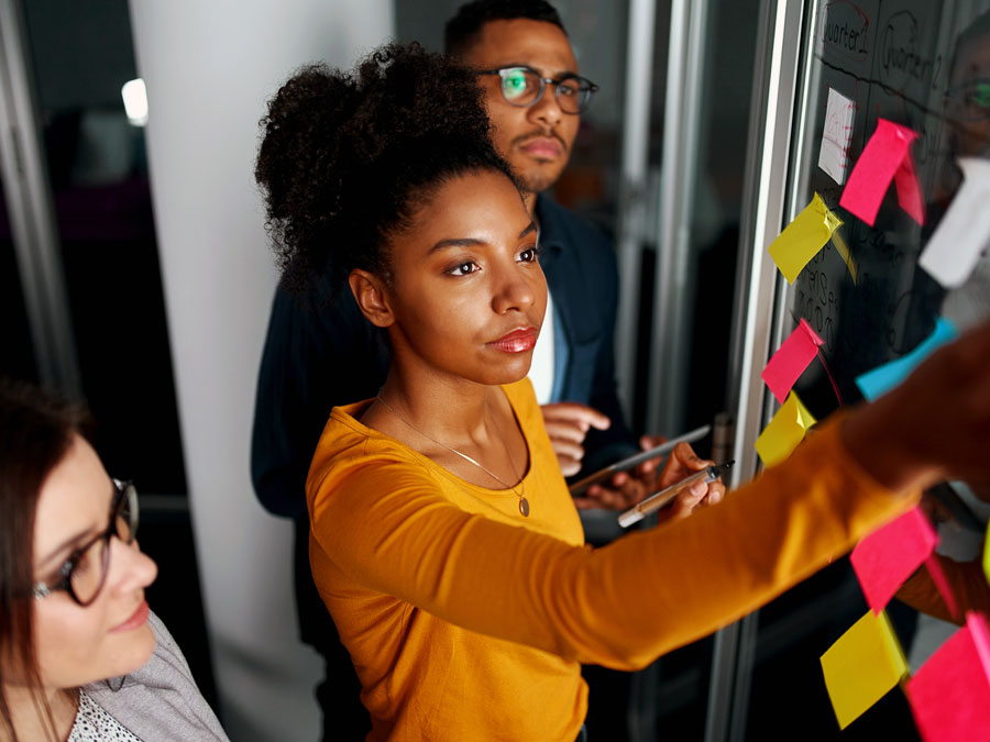 diverse workplace team leader putting post it notes business planning with team