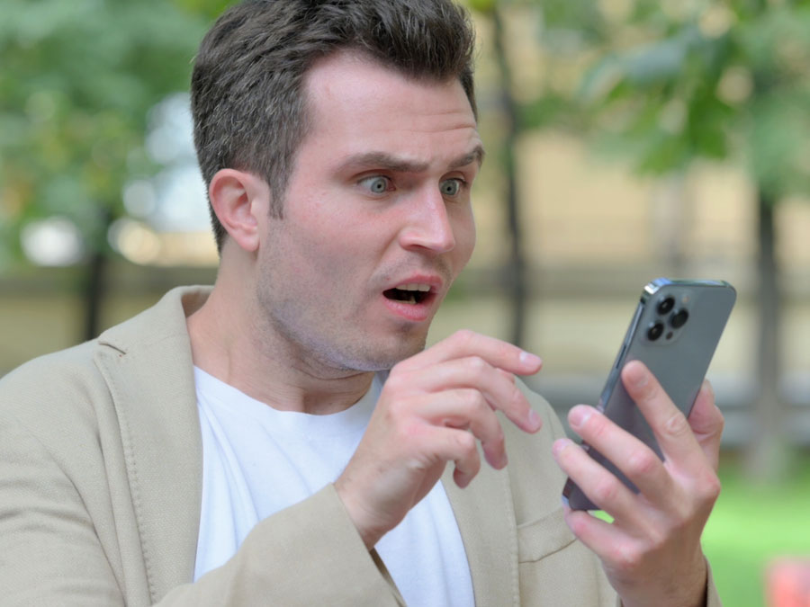 content moderation services annoyed man looking at fake reviews on smartphone