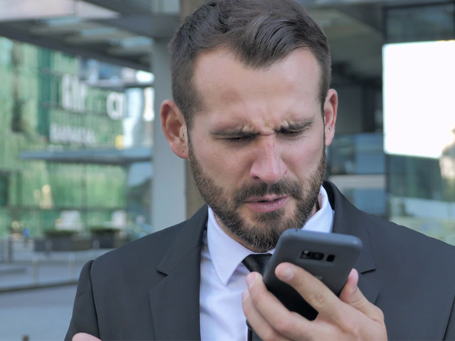 content moderation services annoyed man squinting eyes staring at smartphone in disbelief