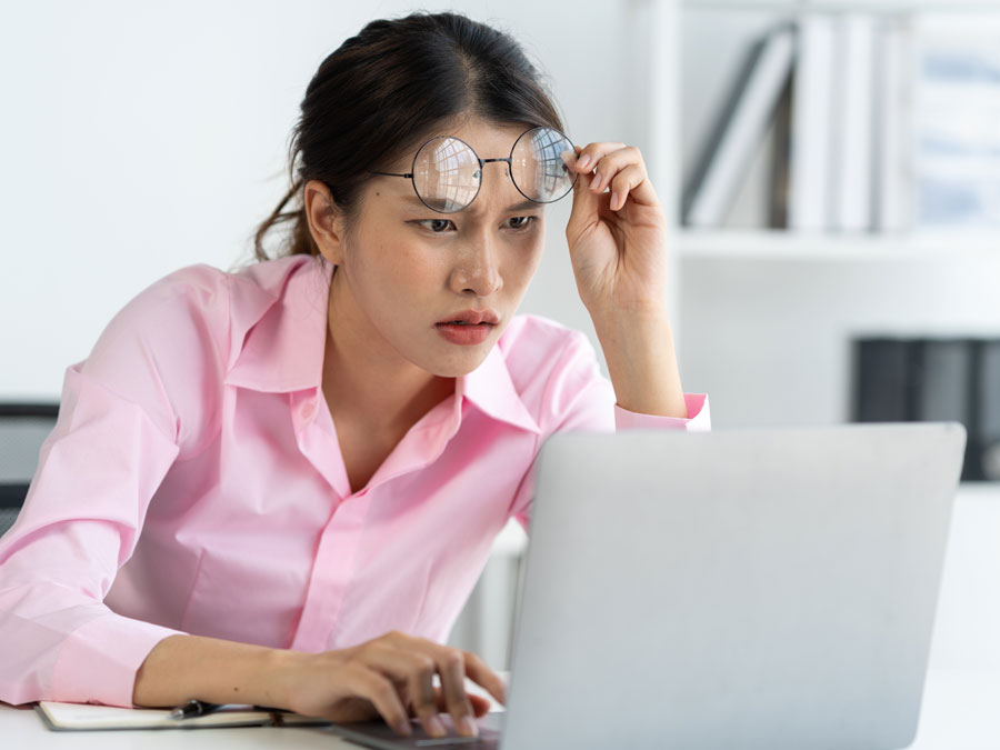 content moderation services surprised woman removing glasses staring at laptop in disbelief