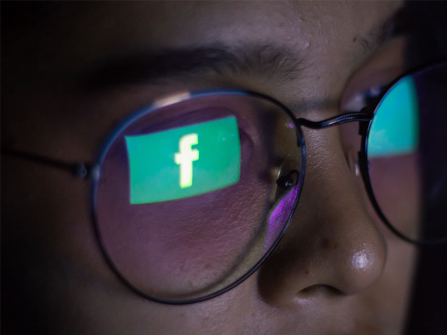 social media customer service close up facebook logo reflecting on female user glasses