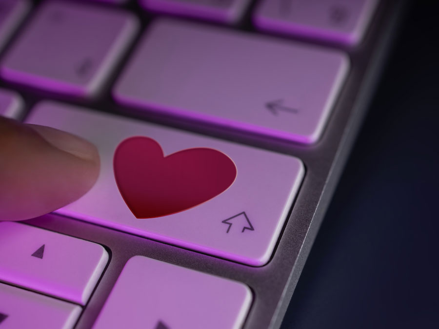 social media customer service depicting empathy CX agent hand pressing heart on computer keyboard