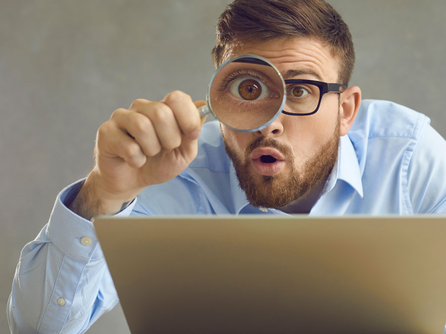 content moderator using magnifying lens on laptop