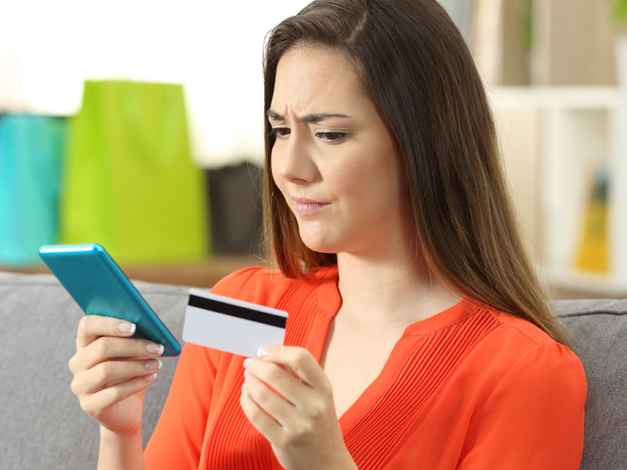 doubtful repeat customer looking at credit card smartphone mobile phone on ecommerce online shopping