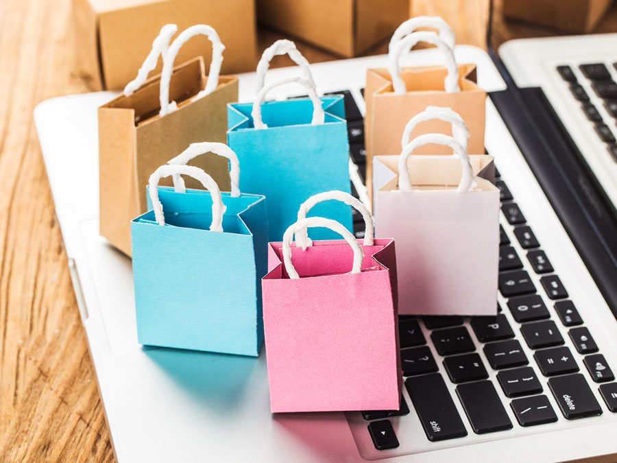 e-commerce depiction multi-colored miniature shopping bags on laptop
