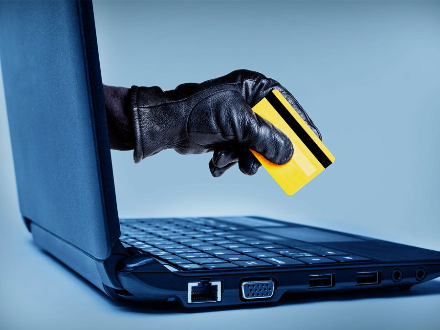 ecommerce fraud cybercrinical hand coming out of laptop screen stealing credit card 
