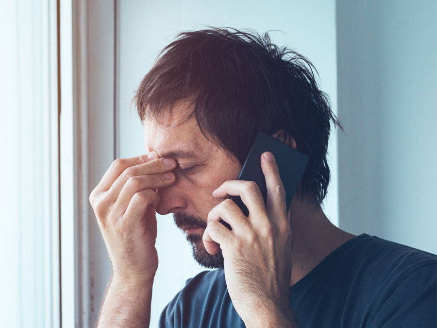 frustrated customer on the phone by window in breaking bad news depiction