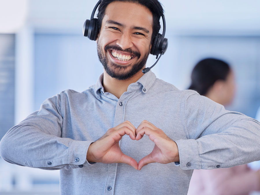 smiling customer satisfaction rep in call center doing heart hand gesture
