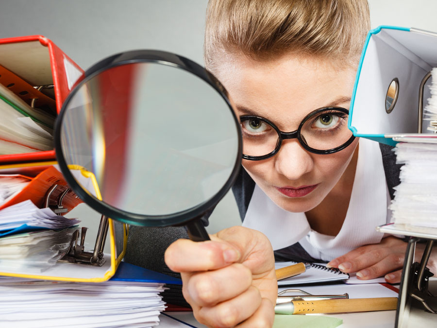 social media content moderation depiction woman holding magnifying lens near binders