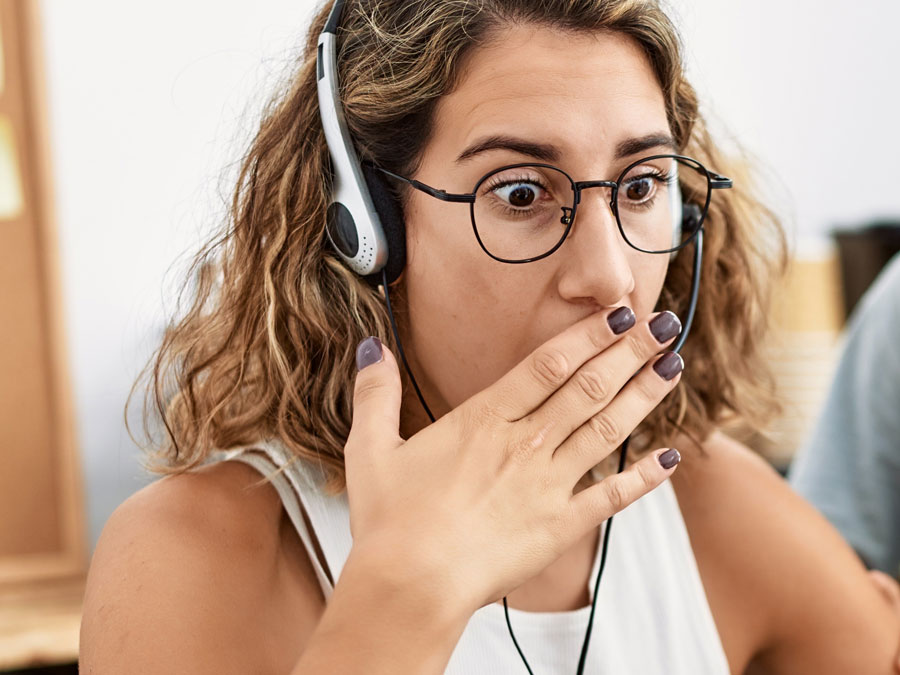 surprised call center agent covering mouth staring at laptop