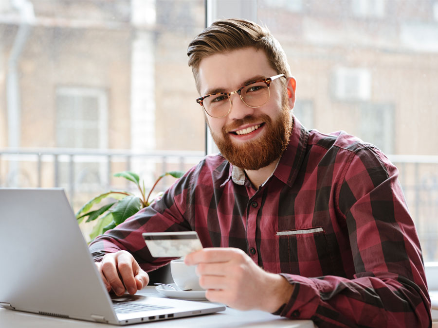 voice of the customer depiction smiling man holding credit card on laptop
