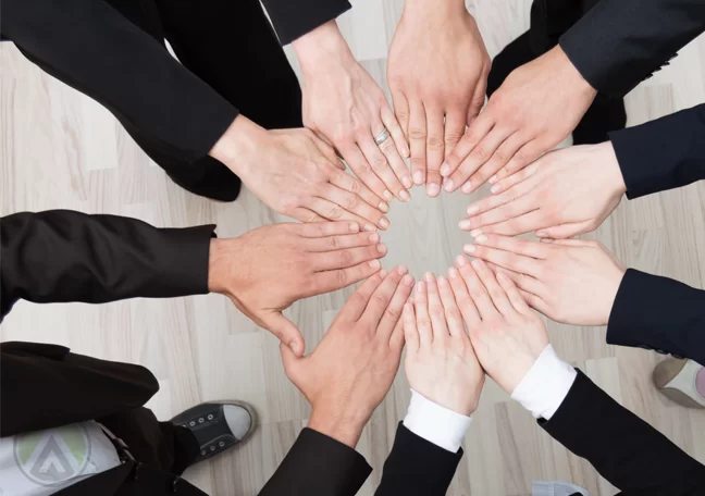 young-millennial-employees-huddled-together-holding-hands-team-work
